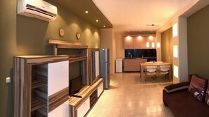 A modern kitchen with built-in appliances, a dining area with a table and chairs, and a living area with a sofa and decorative pillows. - Paradise Gardens & Dunes Hotel (Sozopol)