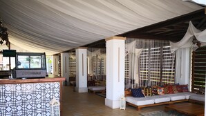A spacious lounge area with a bar, seating arrangements, and a patterned wall. - Paradise Gardens & Dunes Hotel (Sozopol)