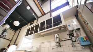 A kitchen with a tiled backsplash, a hanging pot rack, and a window above the sink. - Wabi Sabi Kyoto (Kyoto)