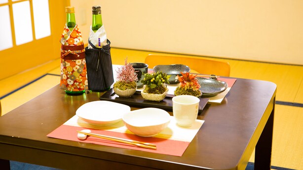 A traditional Japanese dining setup with a table set for two, including plates, bowls, chopsticks, and sake bottles. - Wabi Sabi Kyoto (Kyoto)