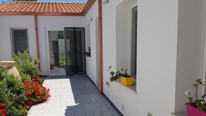 Un sendero estrecho que conduce a un edificio con techo de tejas y puerta de cristal.
