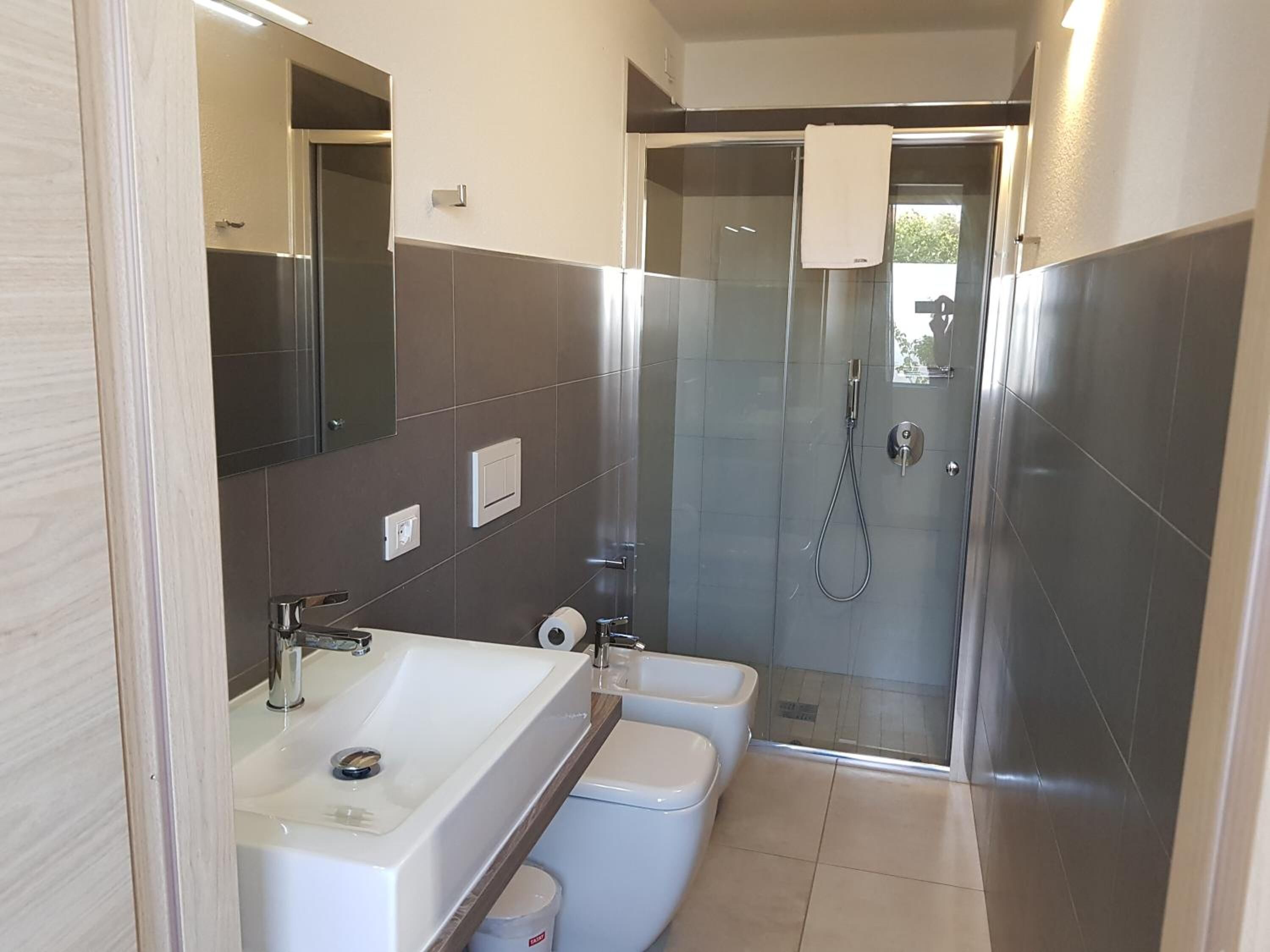 Un baño moderno con lavamanos, inodoro y ducha.