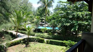 A lush garden with a pool, palm trees, and a gazebo.