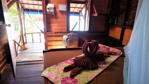 A wooden room with a bed, a fan, and a window.