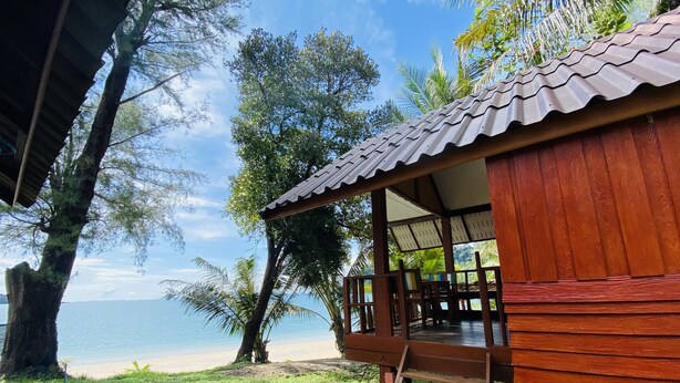 A wooden cabin with a balcony overlooking a beach.