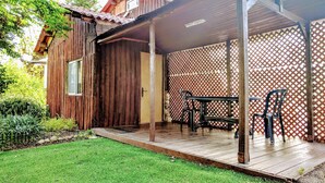Une maison en bois avec un porche couvert, une petite table et deux chaises.