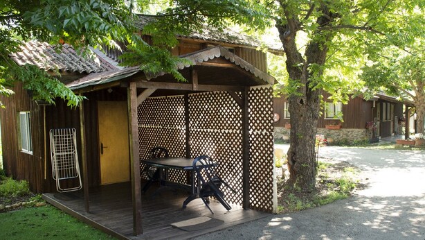A wooden structure with a covered patio, a table, and chairs. - Beit Nofesh Waiss (Mevoot HaHermon)