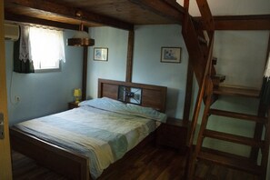A bedroom with a wooden bed, a nightstand, a window with lace curtains, and a wooden ladder. - Beit Nofesh Waiss (Mevoot HaHermon)