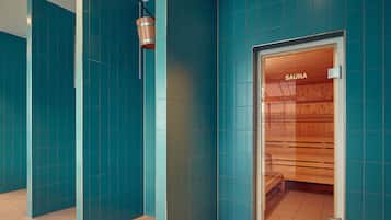 Un pasillo con paredes color turquesa y una sauna visible a través de una puerta de madera.