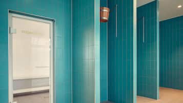 Relax in the steam room, featuring a wooden bucket and teal-tiled walls.