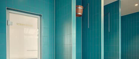Un baño de vapor con paredes verde azulado y una puerta blanca.