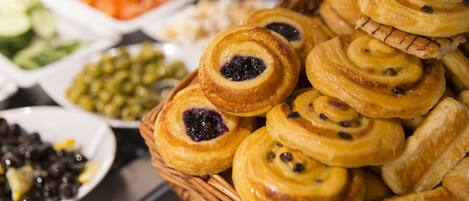 A buffet with various food items including pastries, fruits, and vegetables.