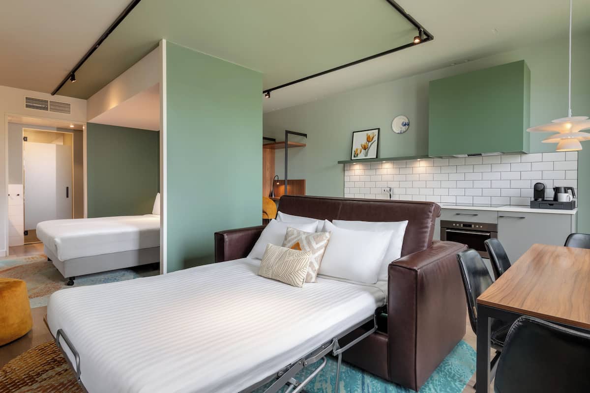 Ein Hotelzimmer mit Bett, einer Couch, einem Esstisch und einer Küchenzeile.