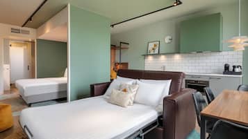 Una habitación de hotel con cama, sofá, mesa de comedor y kitchenette.