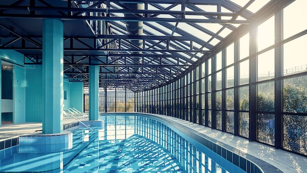 A large indoor swimming pool with clear glass walls, a curved design, and a view of the outdoors. - Corendon Urban Amsterdam Schiphol Airport Hotel (Badhoevedorp)