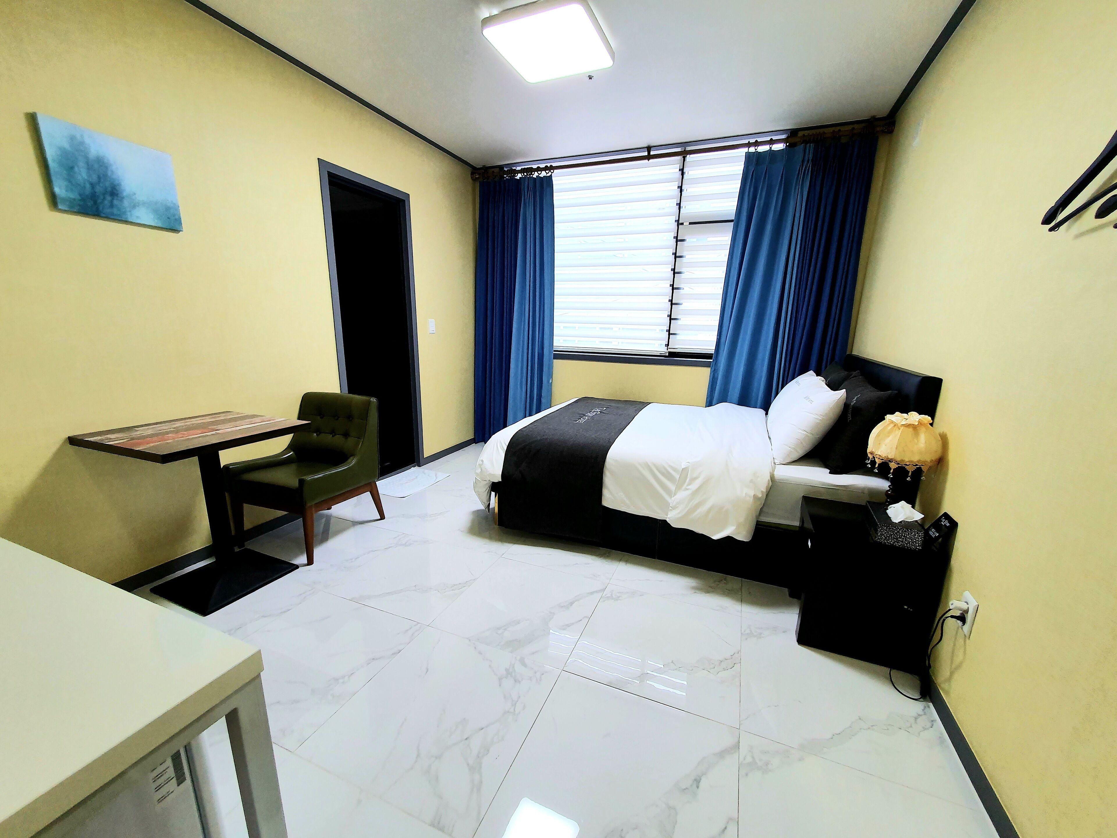 Una habitación de hotel con una cama, un escritorio, una silla y una ventana con cortinas.