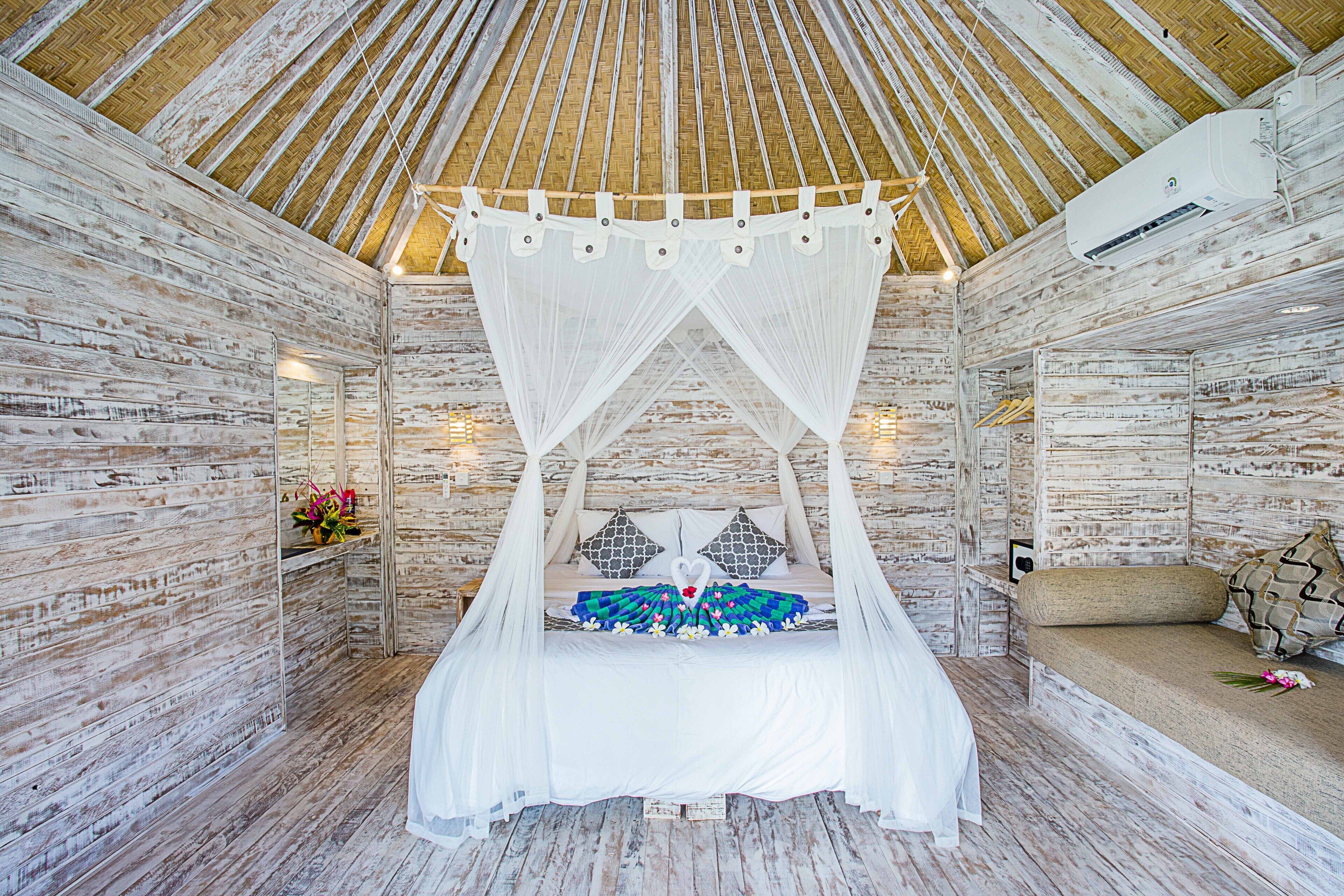 A room with a bed under a canopy, wooden walls, and an air conditioning unit.
