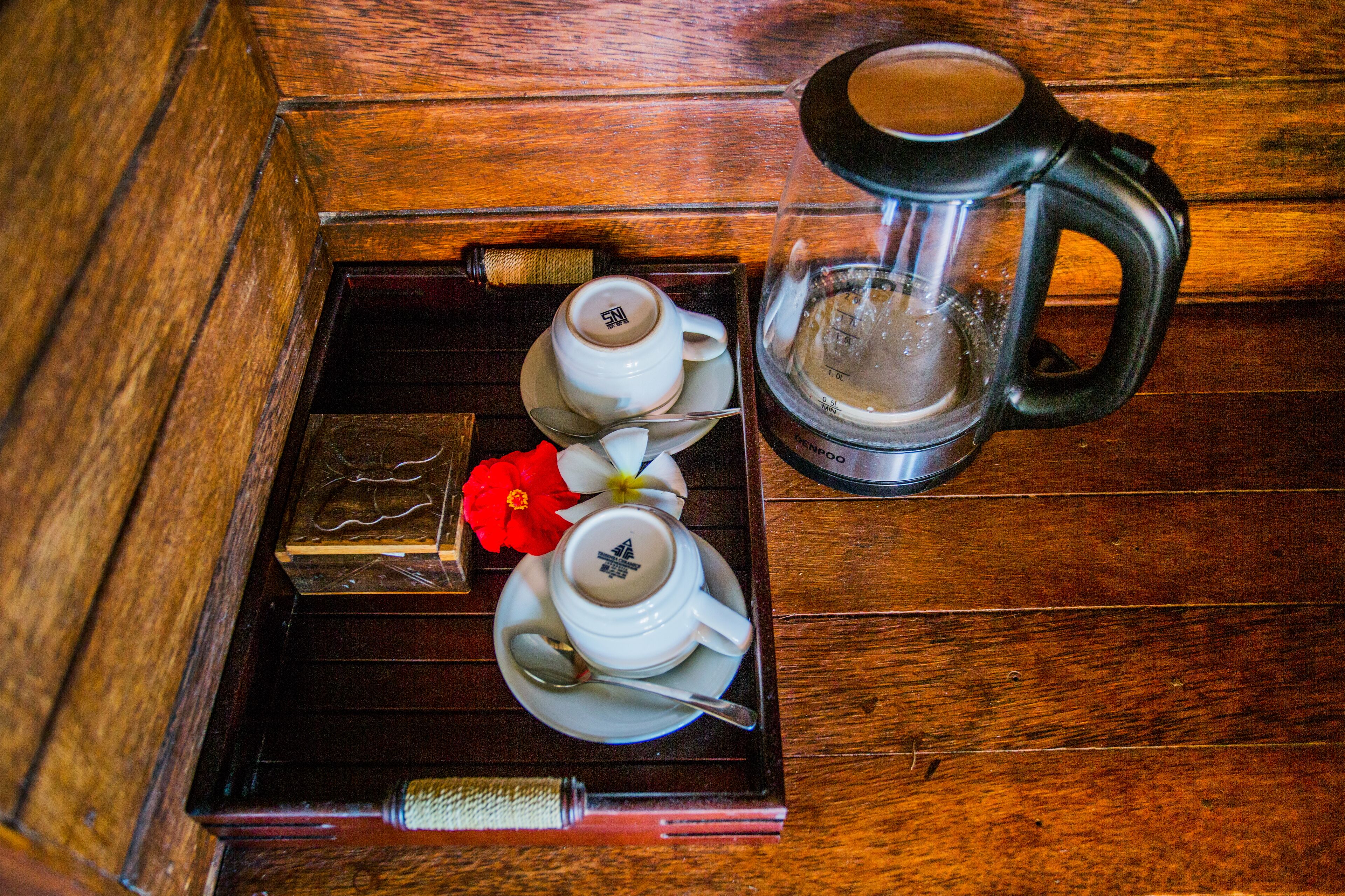 A tray with a teapot, cups, and a glass pitcher on a wooden surface.