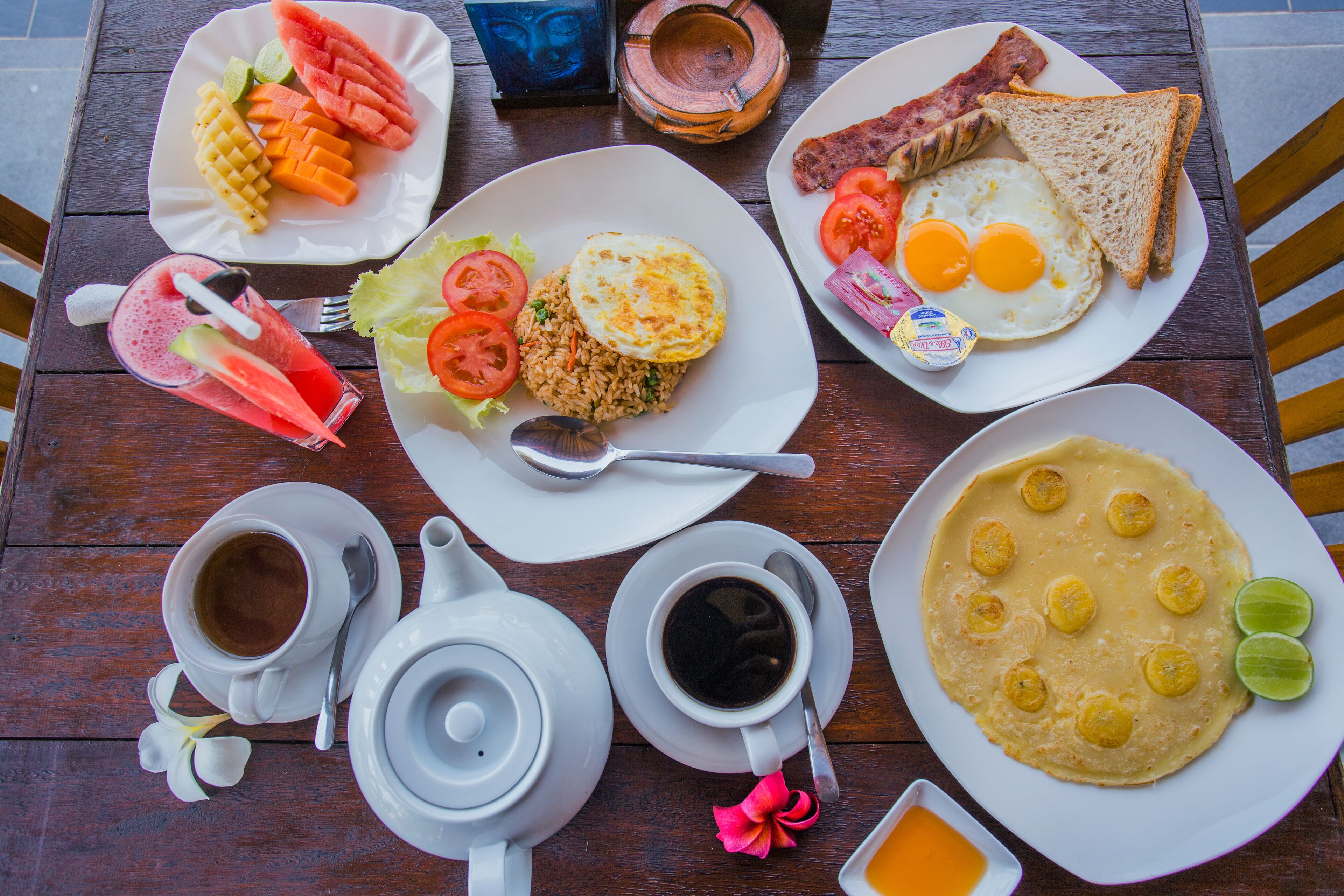 A wooden table with breakfast items including eggs, toast, and a plate of fruit.