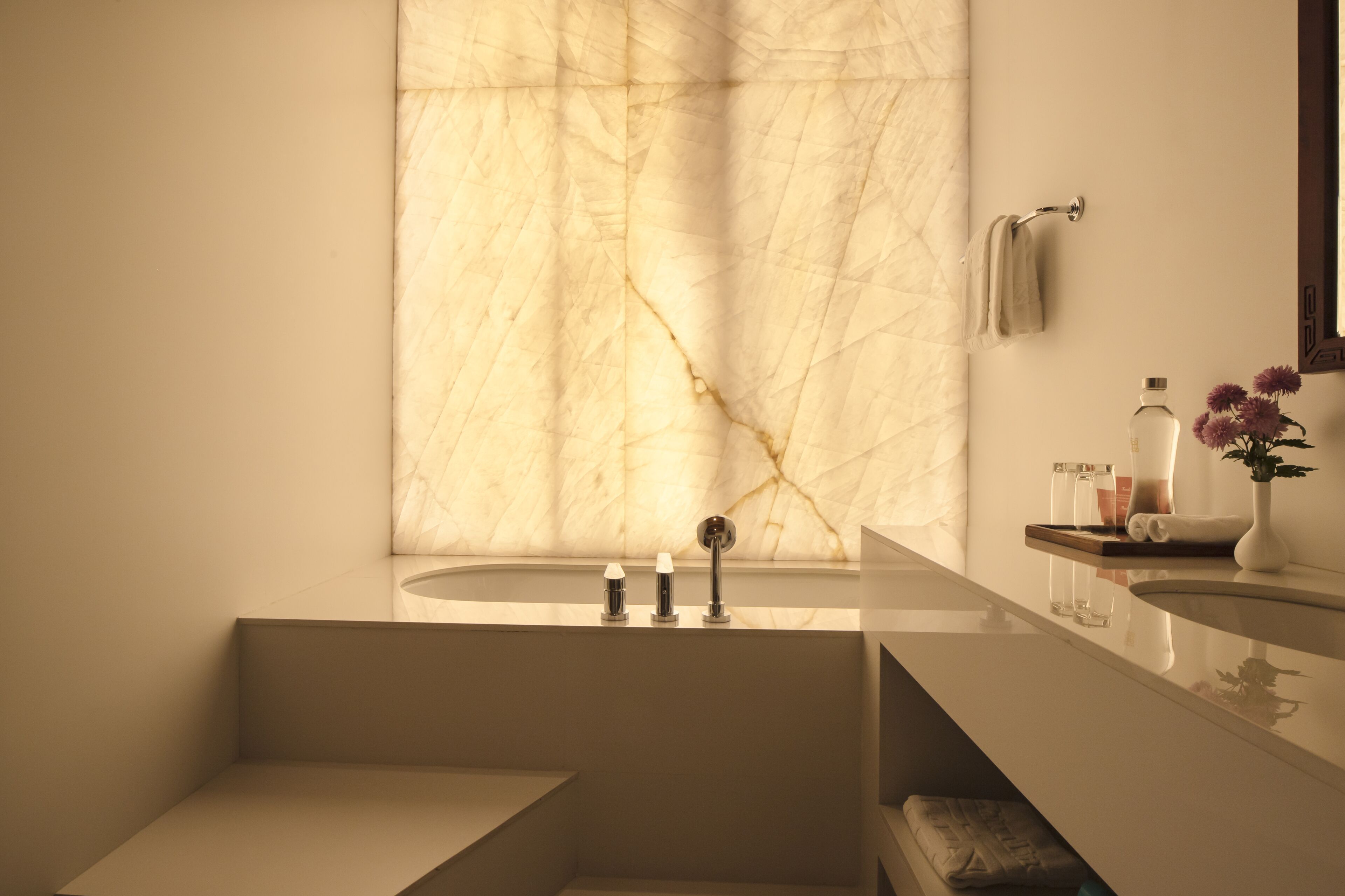 A modern bathroom with a marble wall, a sink, and a mirror.