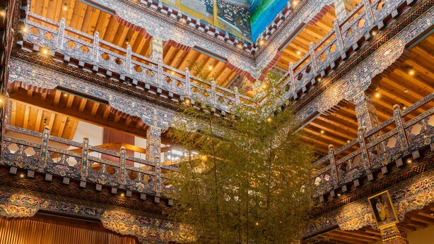 Een meerverdiepings atrium met sierlijke houten balustrades en een centrale boom.