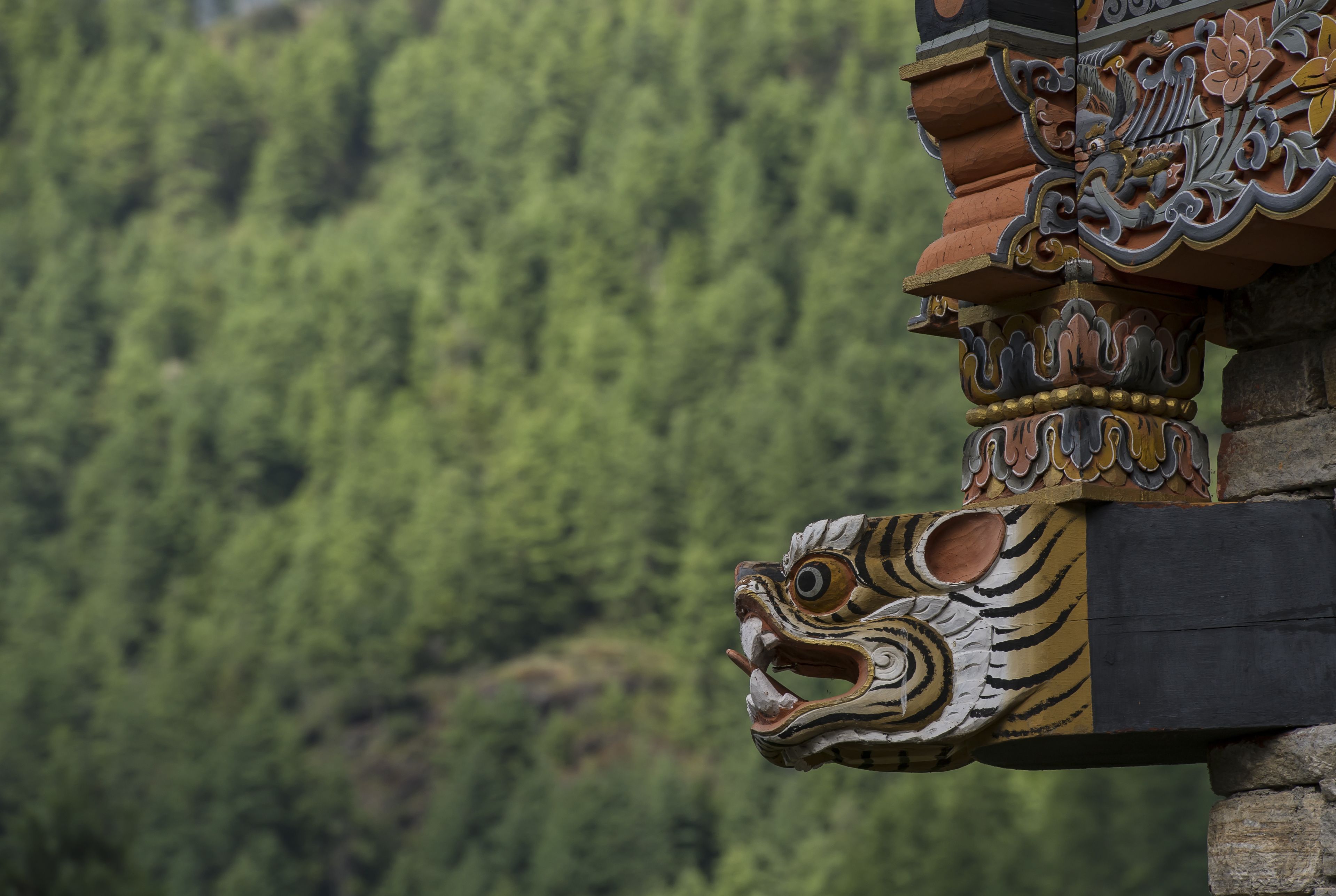 Une structure traditionnelle en bois, ornée de sculptures complexes, se dressant sur un fond de forêt naturelle.