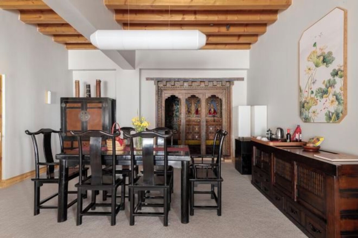 A dining area with a wooden table and chairs, a cabinet with drawers, and a decorative panel on the wall.