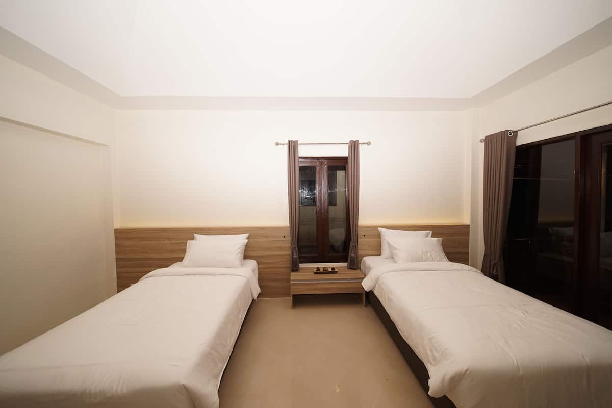 Una habitación de hotel con dos camas individuales, un cabecero de madera, un espejo y una puerta corrediza.
