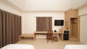 A hotel room with two beds, a desk with a chair, a TV, a wardrobe, and a small cabinet.