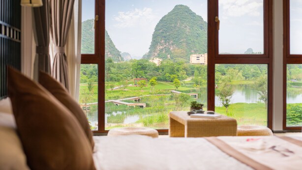 Una habitación con un ventanal grande que da a un paisaje montañoso y un lago.