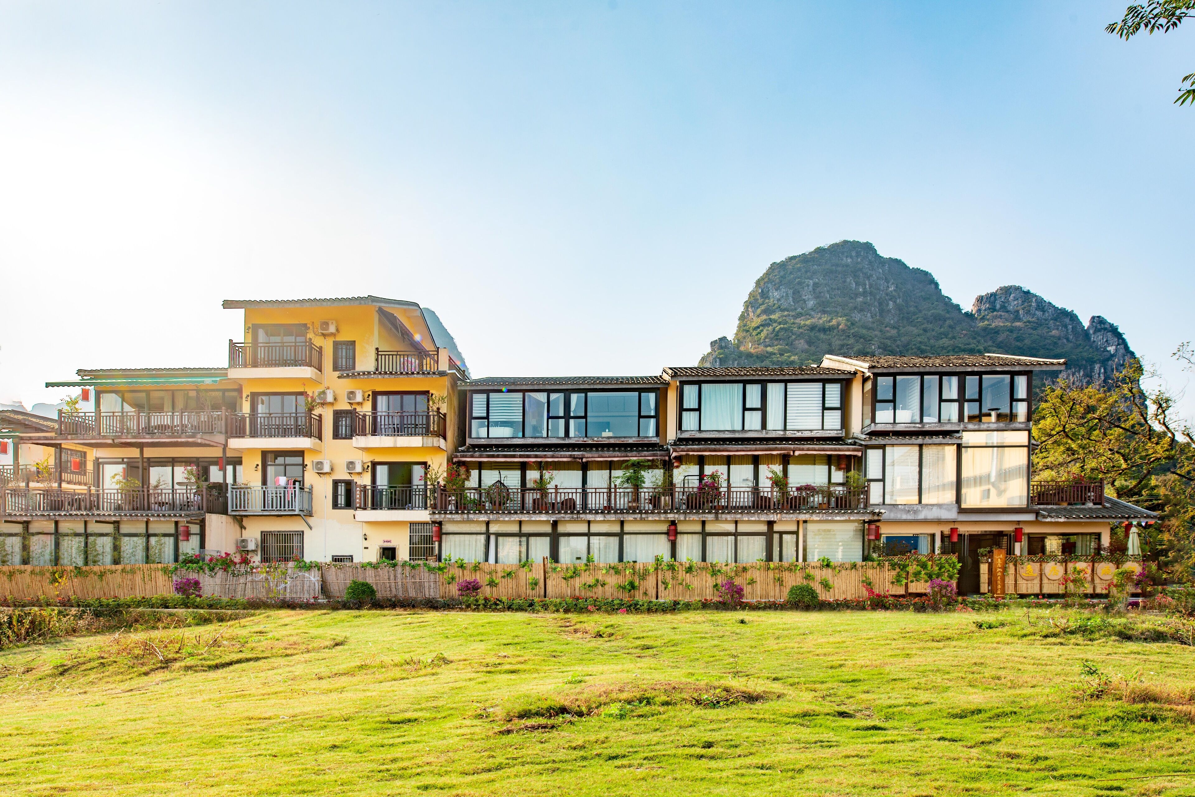A multi-story hotel with balconies, large windows, and a view of a mountain.