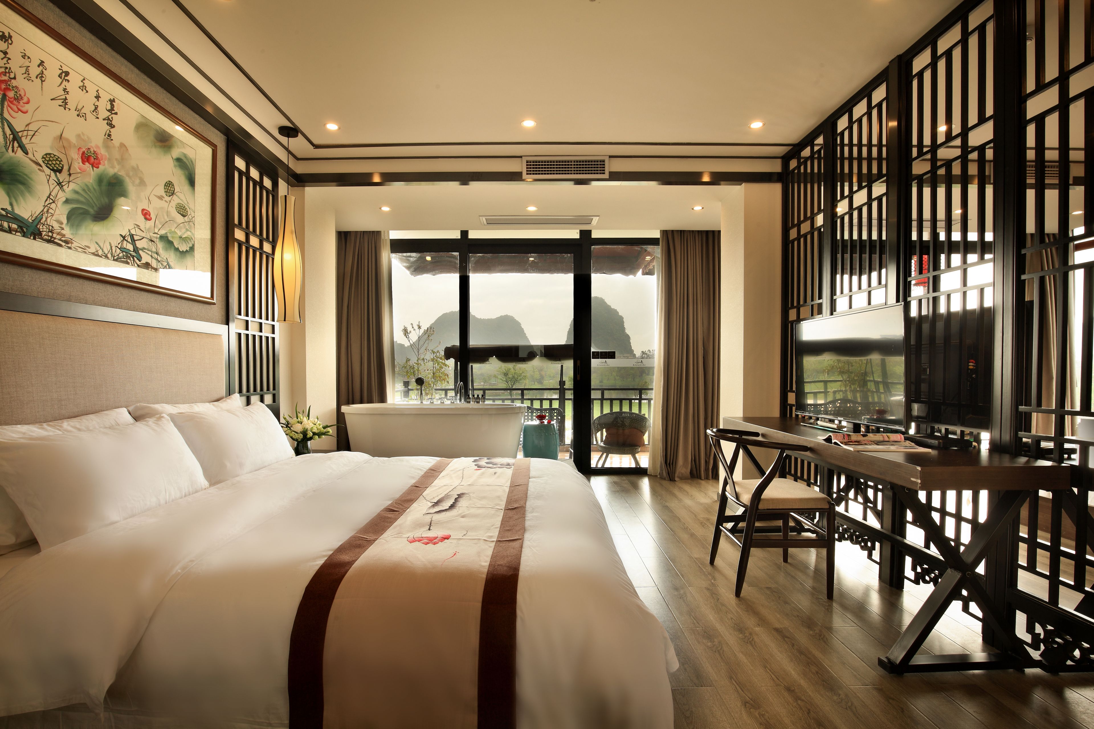 A hotel room with a large bed, a desk, and a view of mountains through the window.