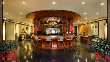 A reception area with a wooden reception desk, three bar stools, and potted plants.