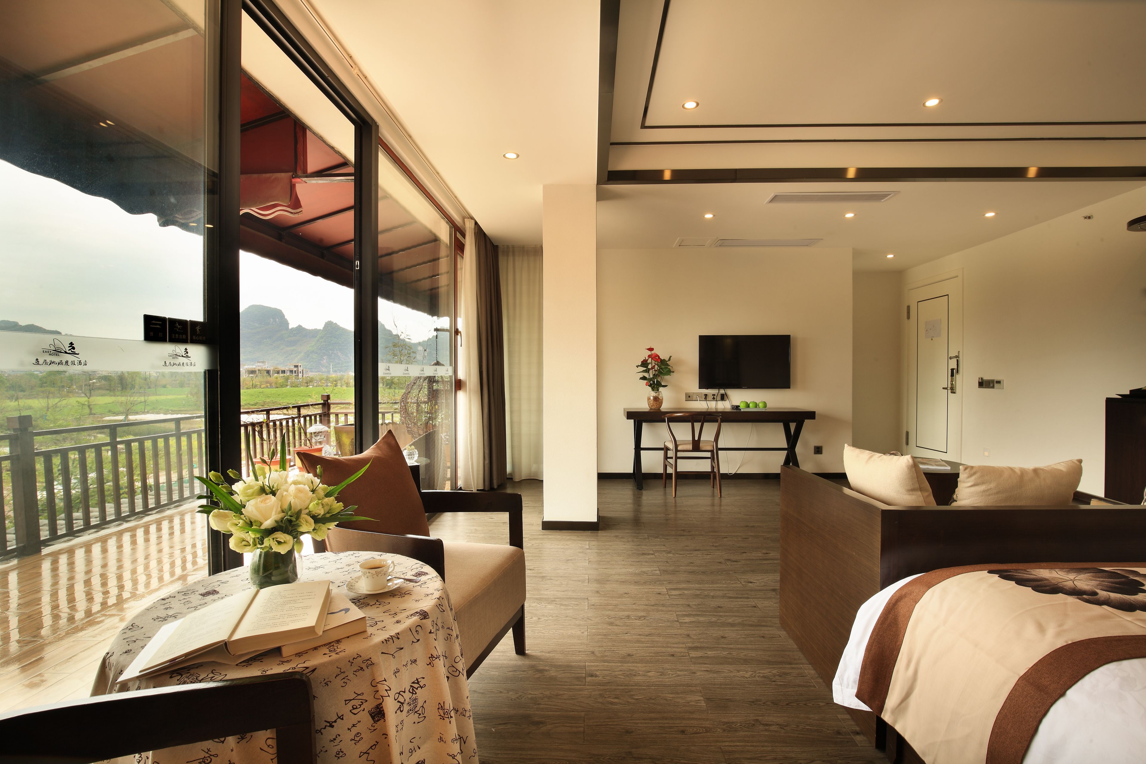 Habitación de hotel con balcón, zona de comedor y cama.