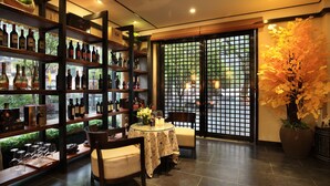 Un restaurante con una bodega de vinos, una mesa de comedor con sillas y una planta grande en maceta.