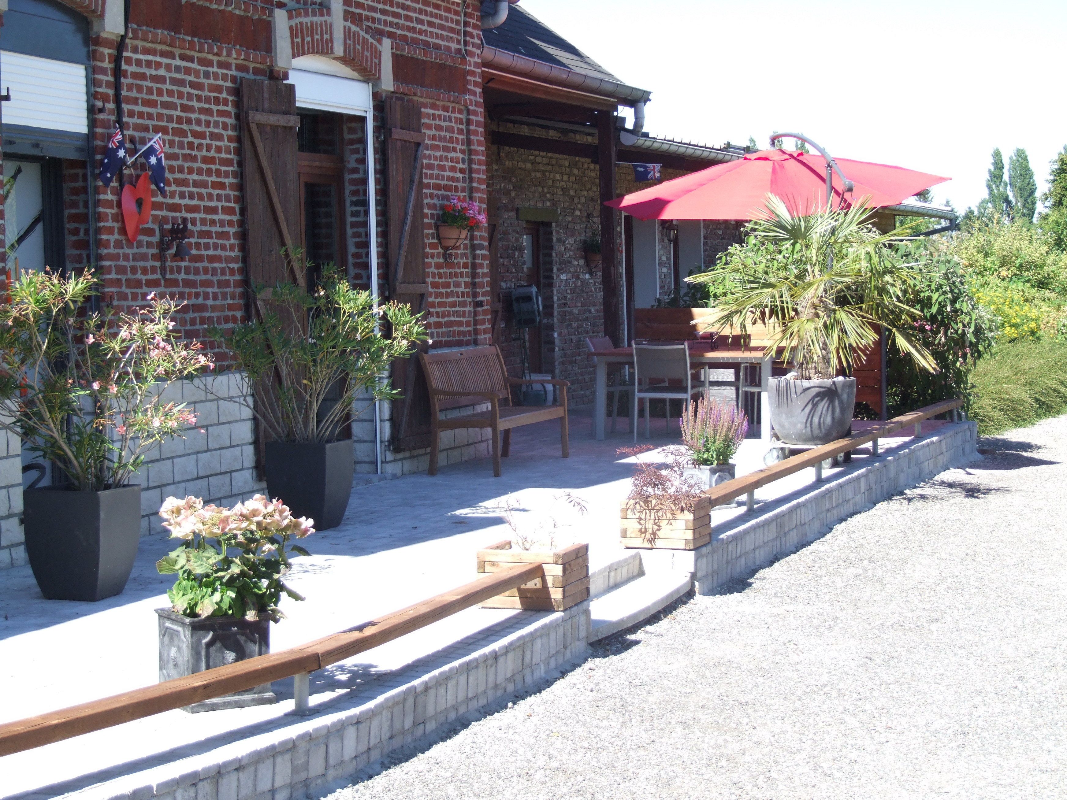 A patio area with outdoor seating, potted plants, and a red umbrella.