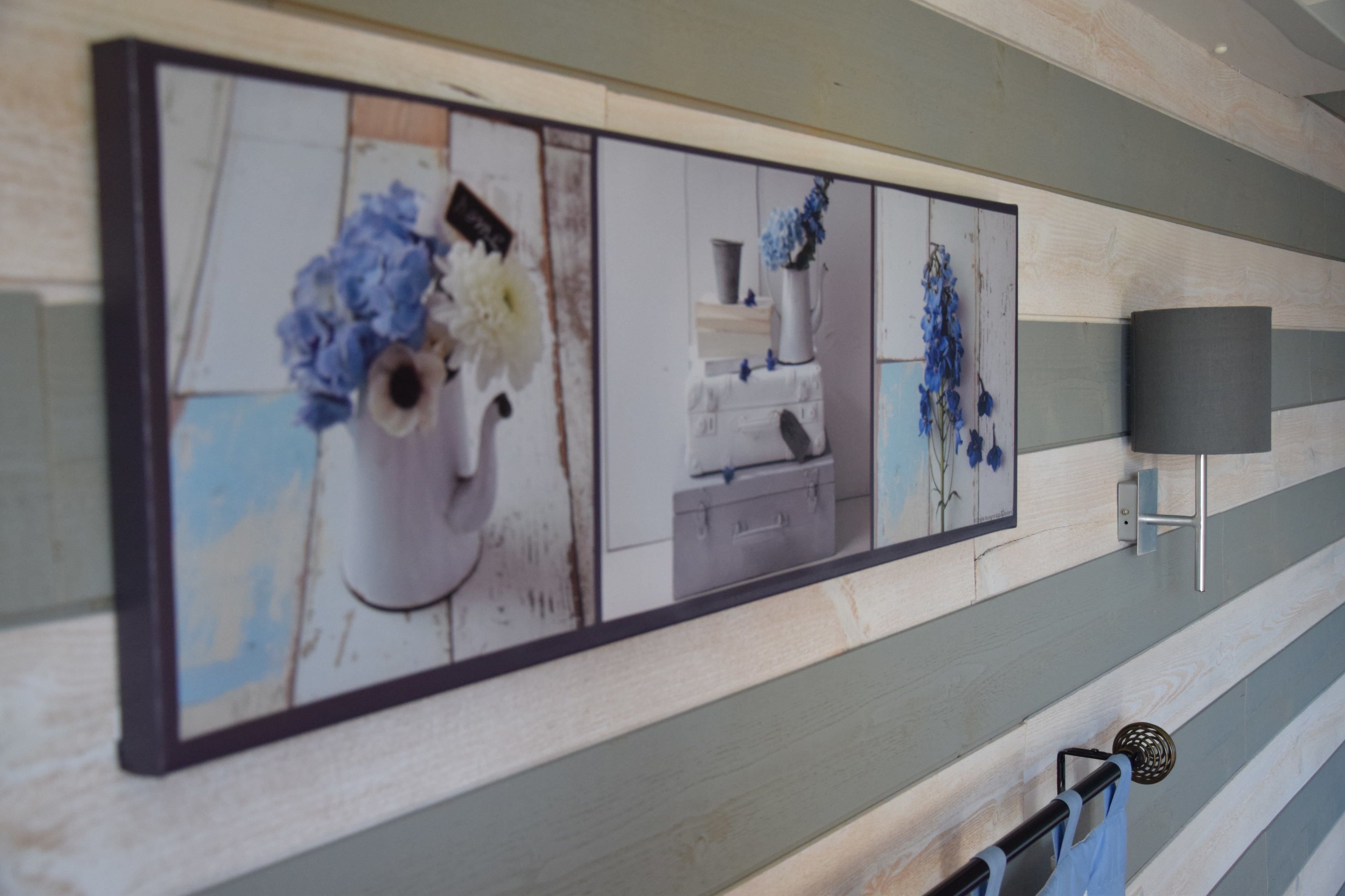 Una pared con varias obras de arte enmarcadas que muestran arreglos florales.