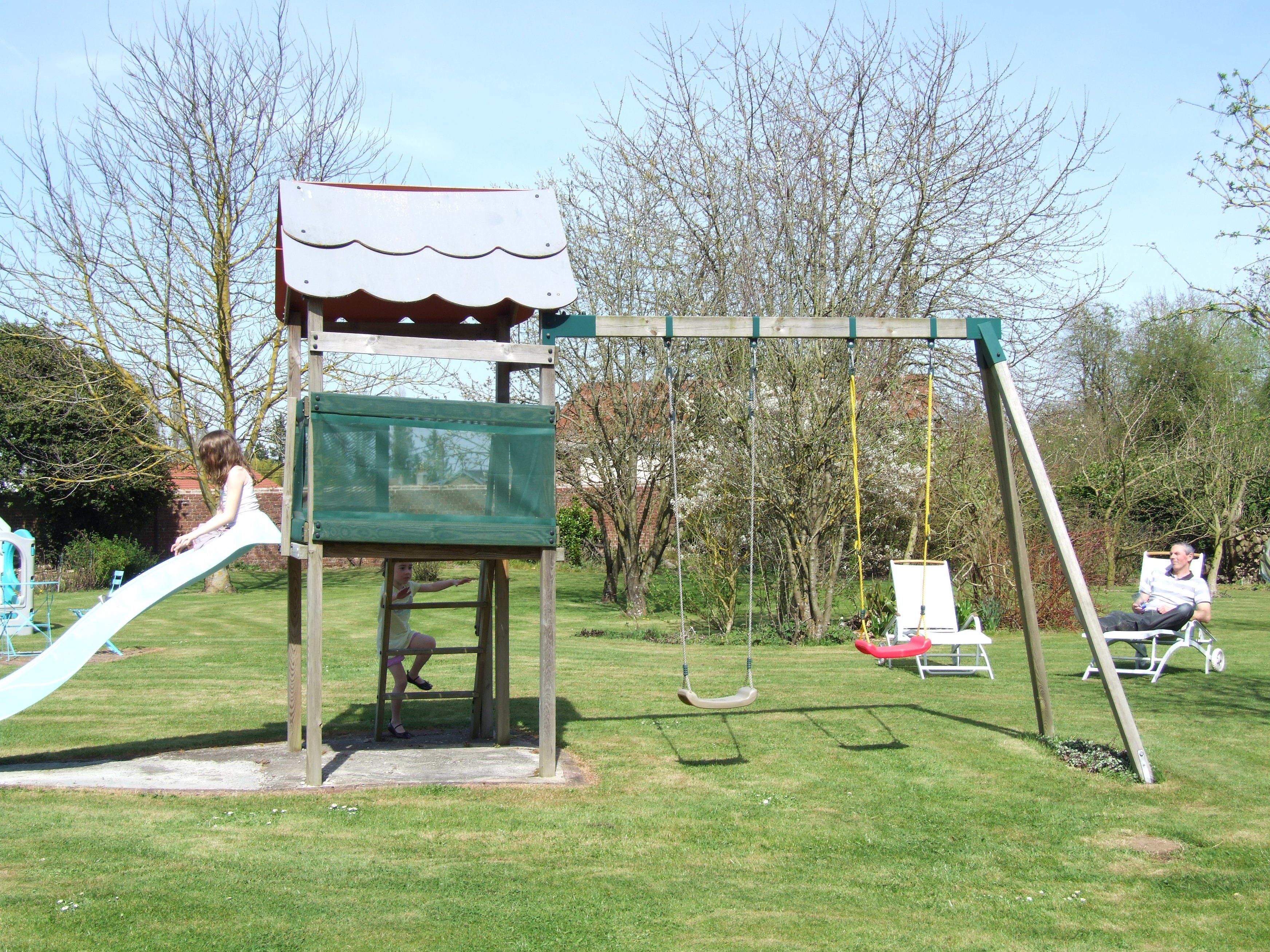 A playground with a slide, swing set, and a covered play area.