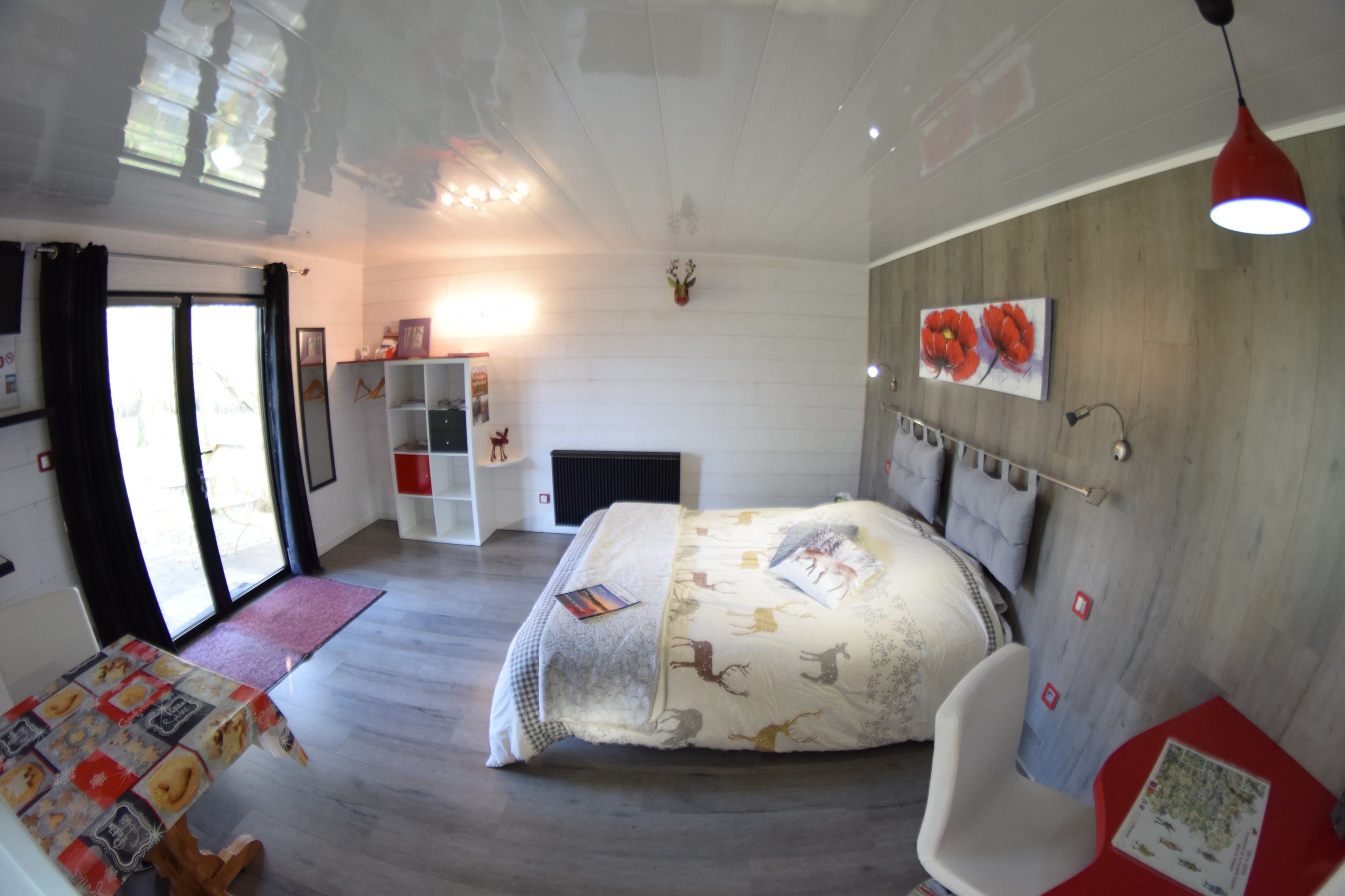 A bedroom with a bed, a desk, a chair, a bookshelf, a fireplace, and a window.
