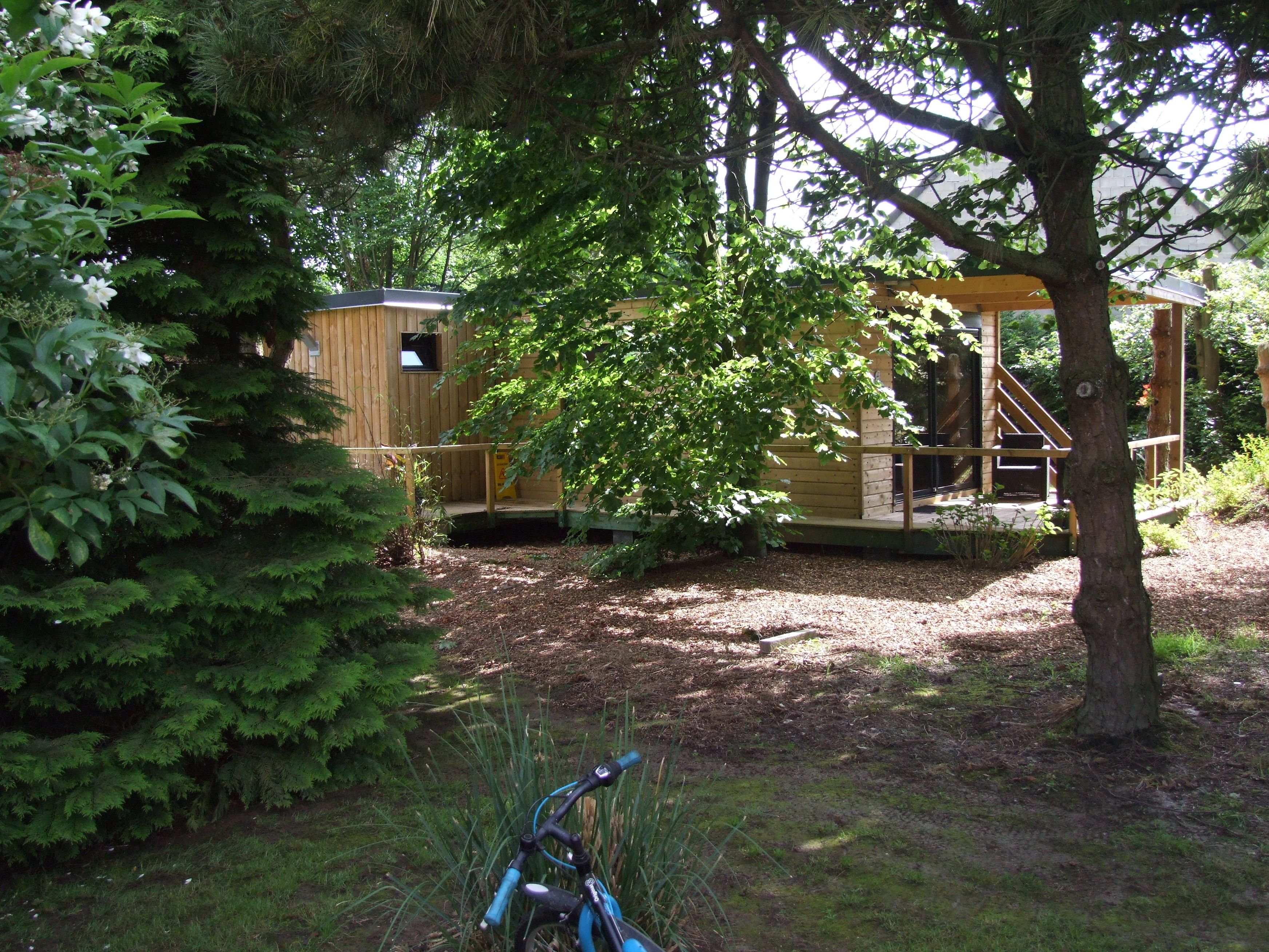 A wooden cabin with a porch and a staircase leading to a deck.