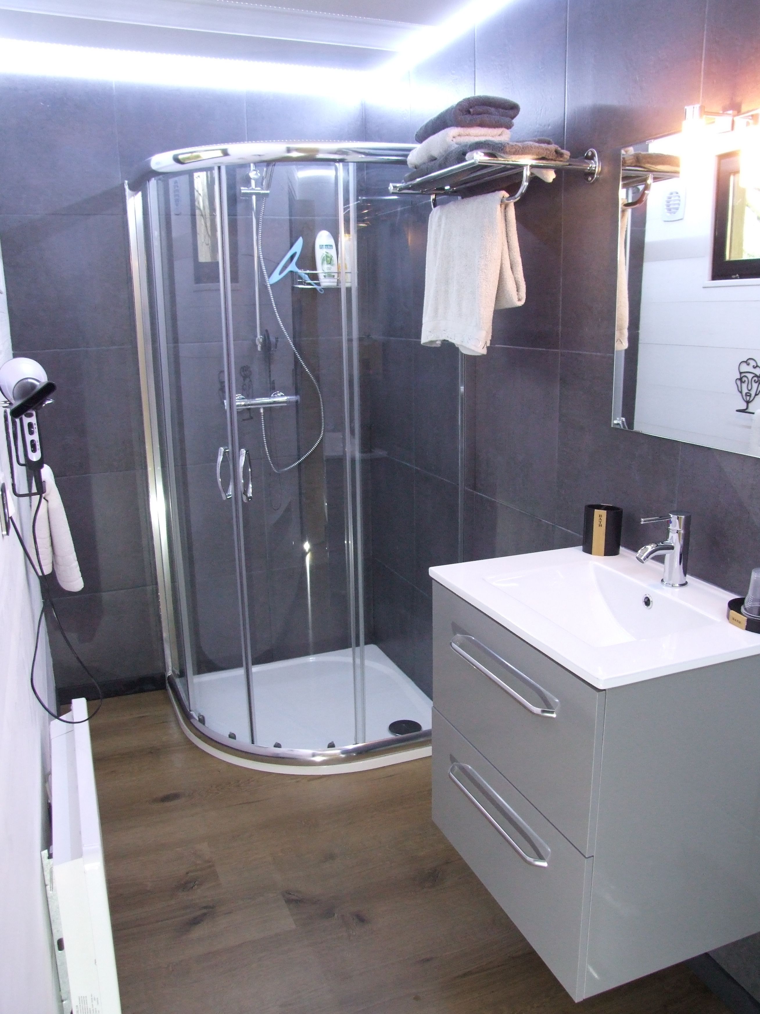 A modern bathroom with a glass-enclosed shower, a white sink, and a mirror above the sink.