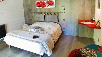 A bedroom with a bed, a headboard, a red pendant light, a small shelf with items, and a chair.