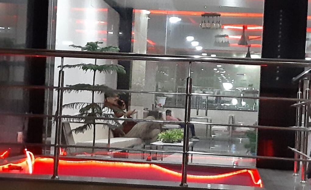 Un moderno vestíbulo con barandilla de vidrio, zona de estar y plantas de interior.