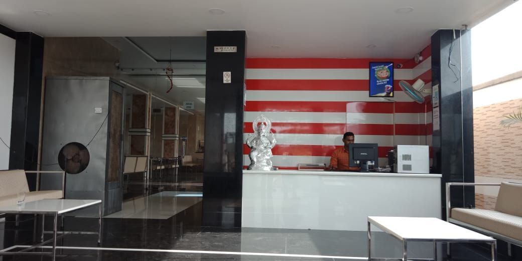 A reception area with a receptionist, a statue, and a counter.