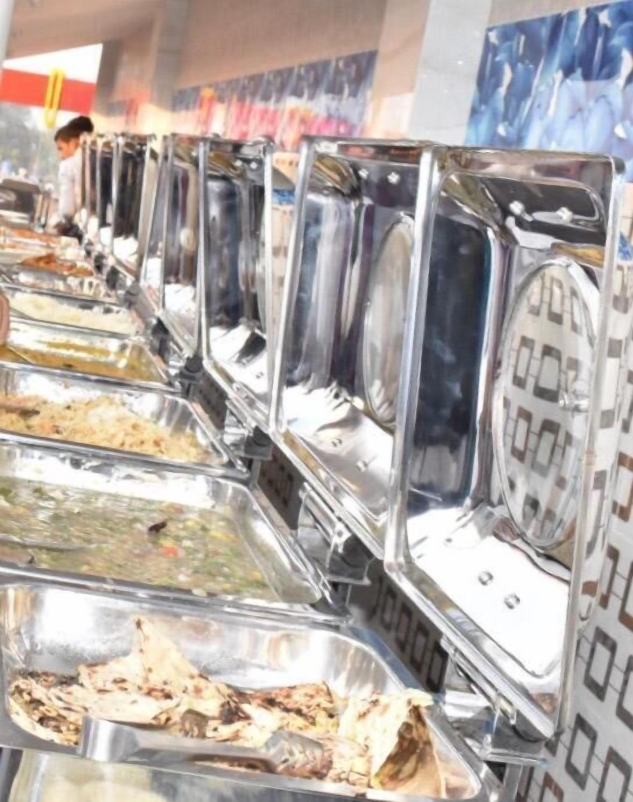 Una barra de buffet con diversos alimentos en fuentes de metal.