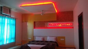 A bedroom with a bed, a ceiling fan, a red neon light strip, and a window with curtains. - Hotel Royal Country Club (Pindra)