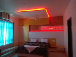 A bedroom with a bed, a ceiling fan, a red neon light strip, and a window with curtains.