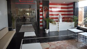 A modern lobby with a reception desk, seating area, and a statue. - Hotel Royal Country Club (Pindra)