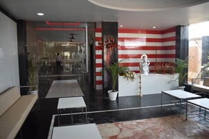Un vestíbulo moderno con una recepción, zona de estar y una estatua.