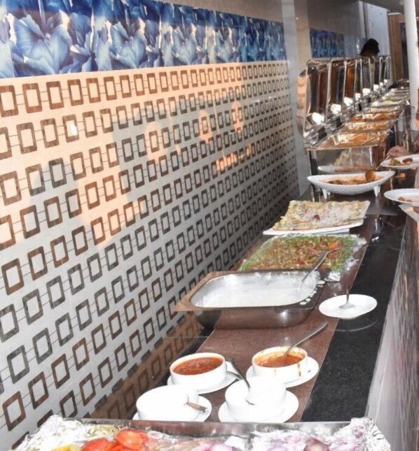 A buffet setup with various dishes and a patterned wall in the background.